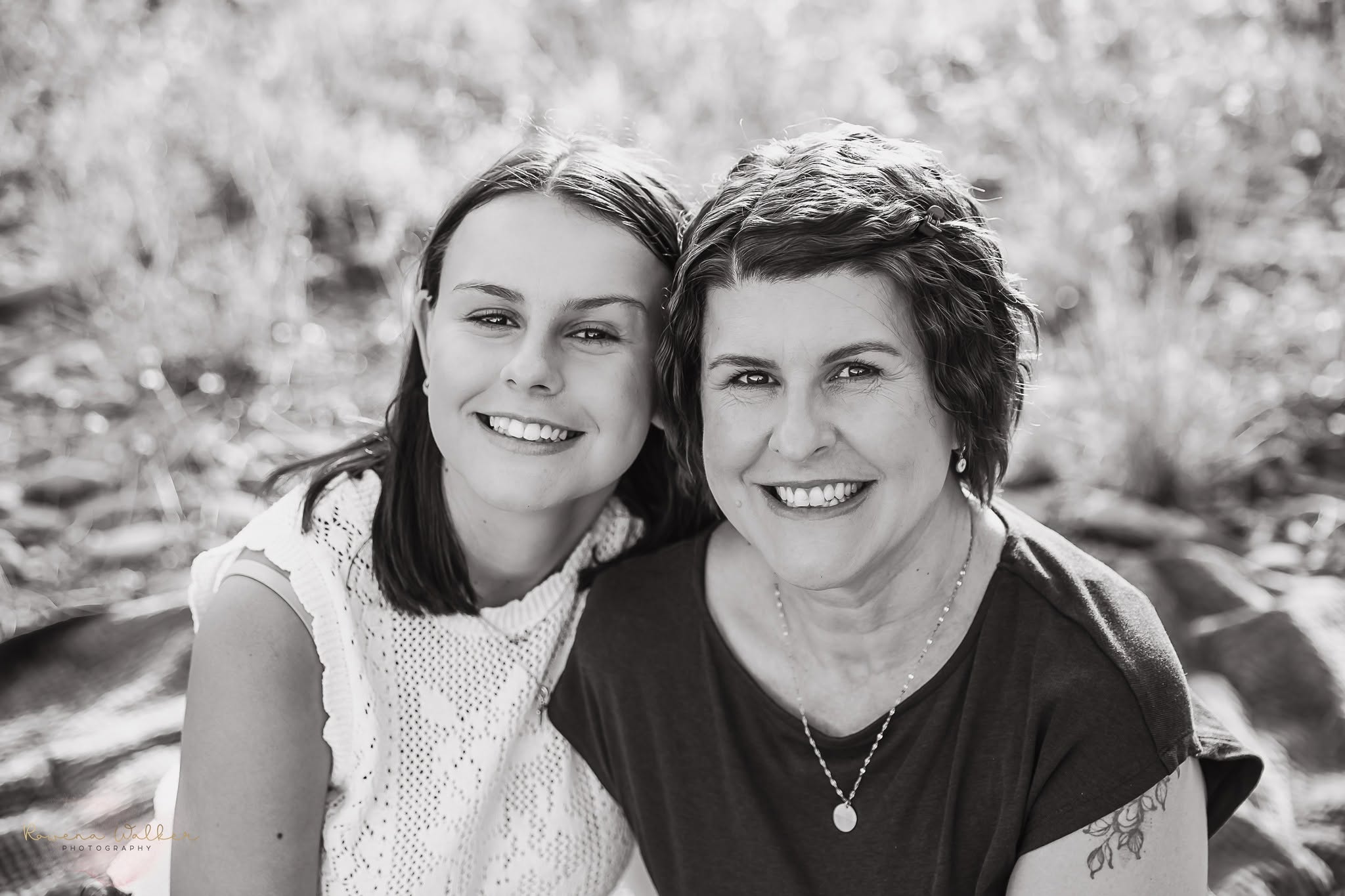 Black and white portrait of a mother and daughter smiling with their heads together