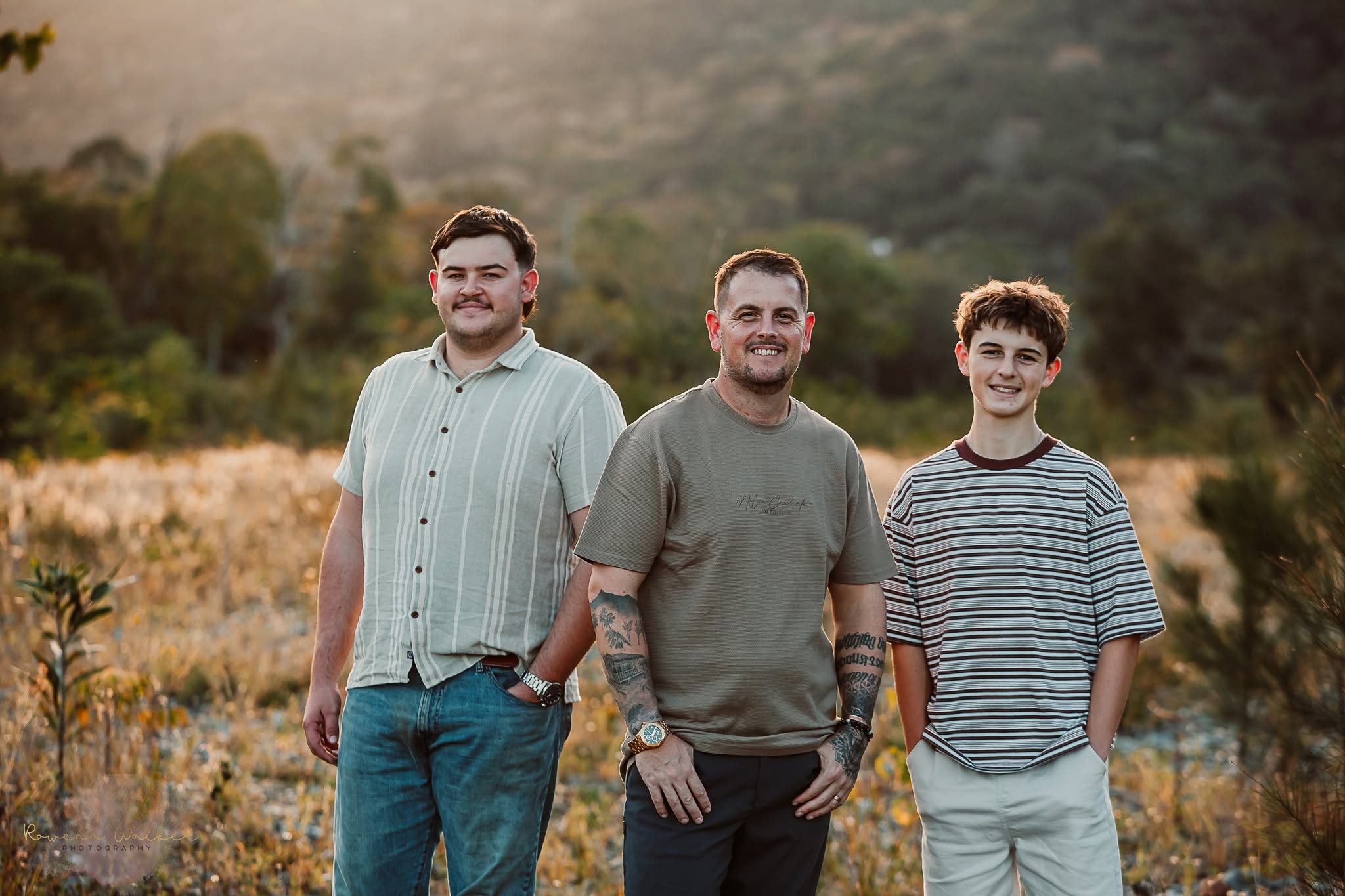 Three smiling men standing together in warm evening light